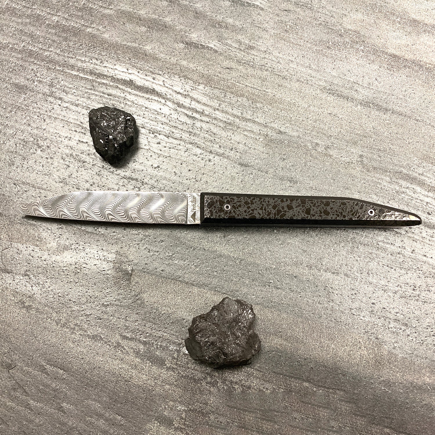 The slag heap: folding knife with its polished charcoal handle and its Damascus blade